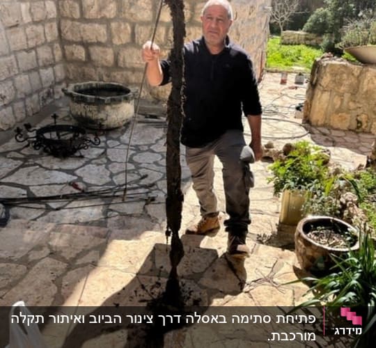 אדם מחזיק צינור עם לכלוך בחצר אבן